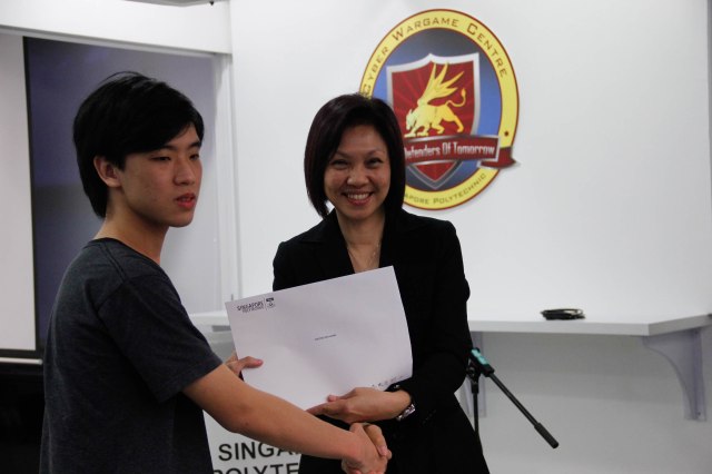 DMIT Director Ms Georgina Phua presenting Certificate of Participation in DISM CTF S1 to year 1 student Cheong Ren Hann